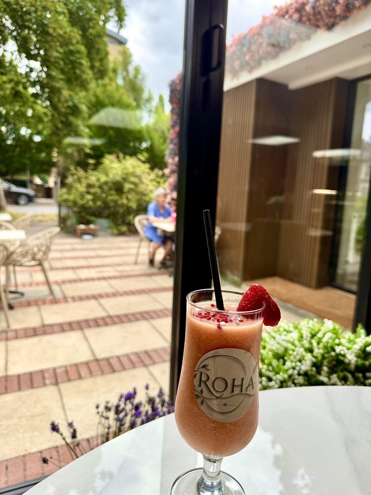 Strawberry smoothie in a branded ROHA glass on the garden terrace